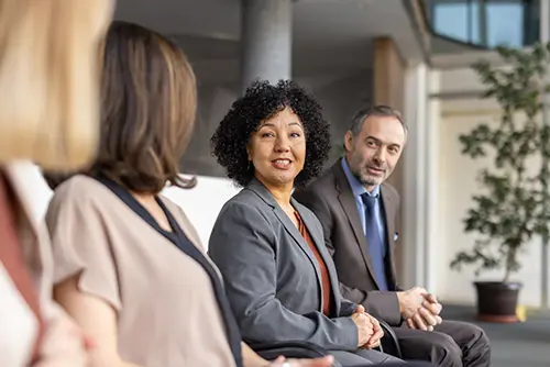A diverse group of professionals discuss and engage, promoting collaboration, connection, and teamwork in an inviting office environment